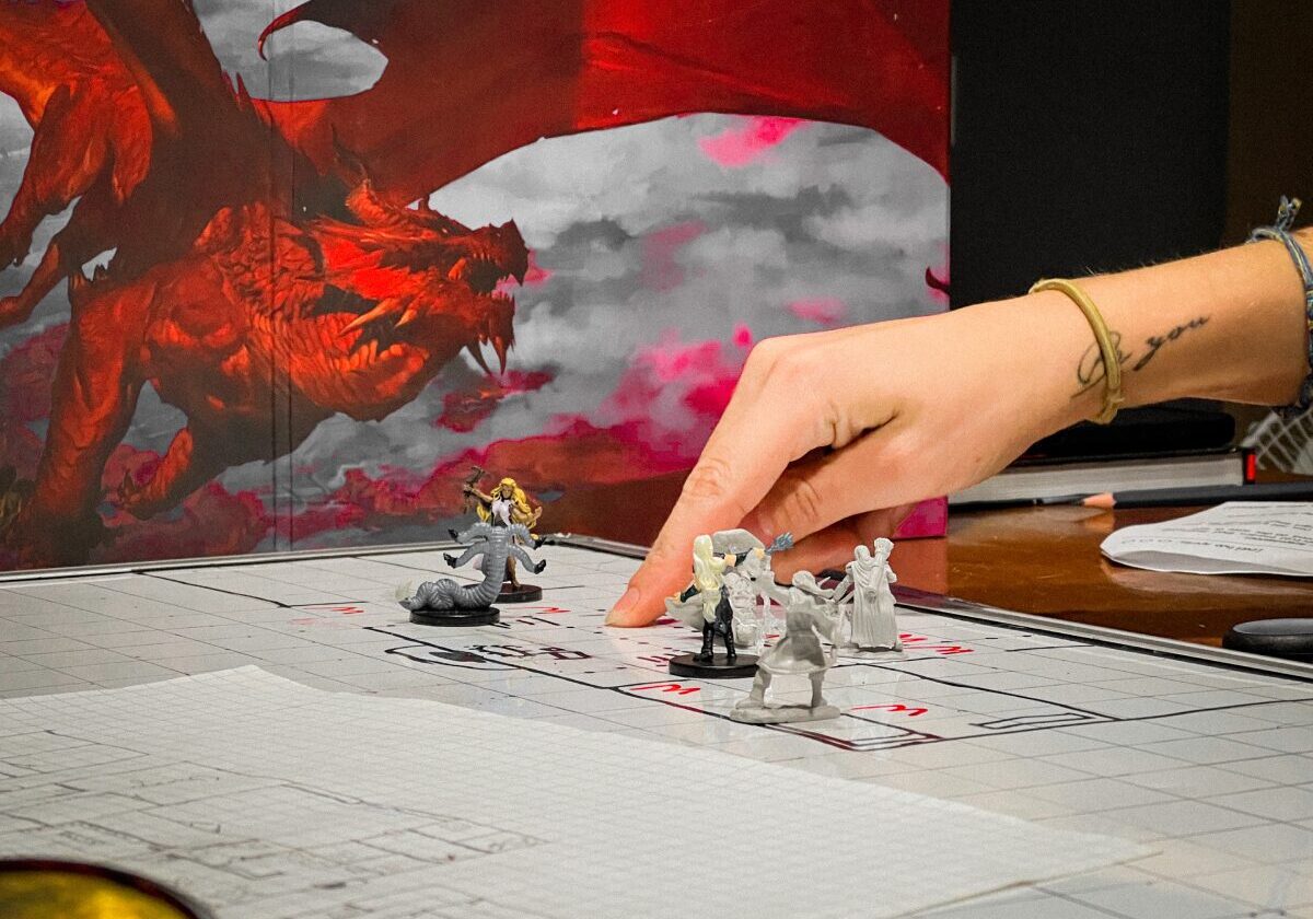 A hand moves miniature figures on a game board with a dragon illustration in the background, evoking a tabletop role-playing game session and offering visual Roleplay Immersion Tips.